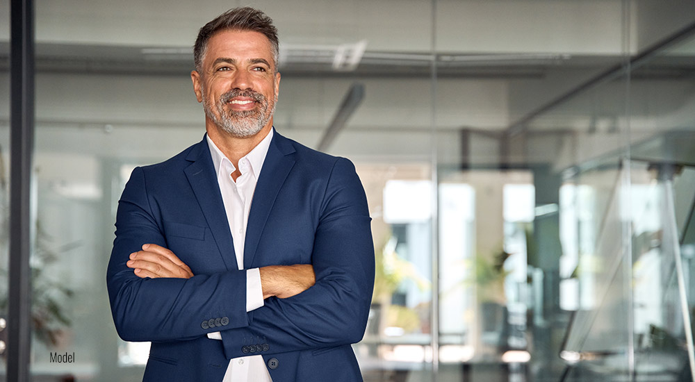 Man stands with his arms crossed in an office